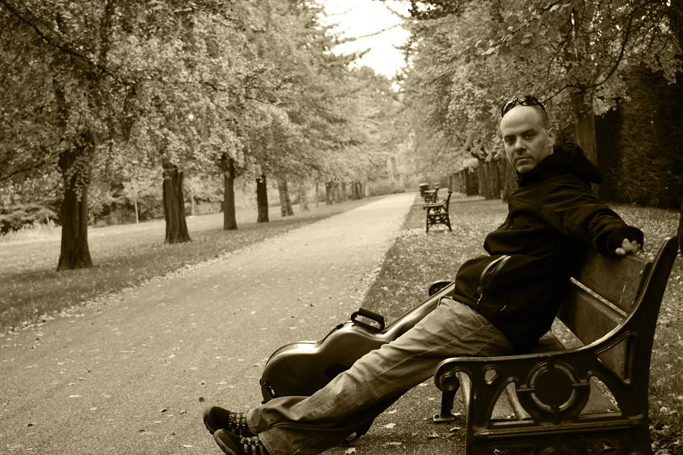 Rhayn Jooste seated on a park bench beside his classical guitar case
